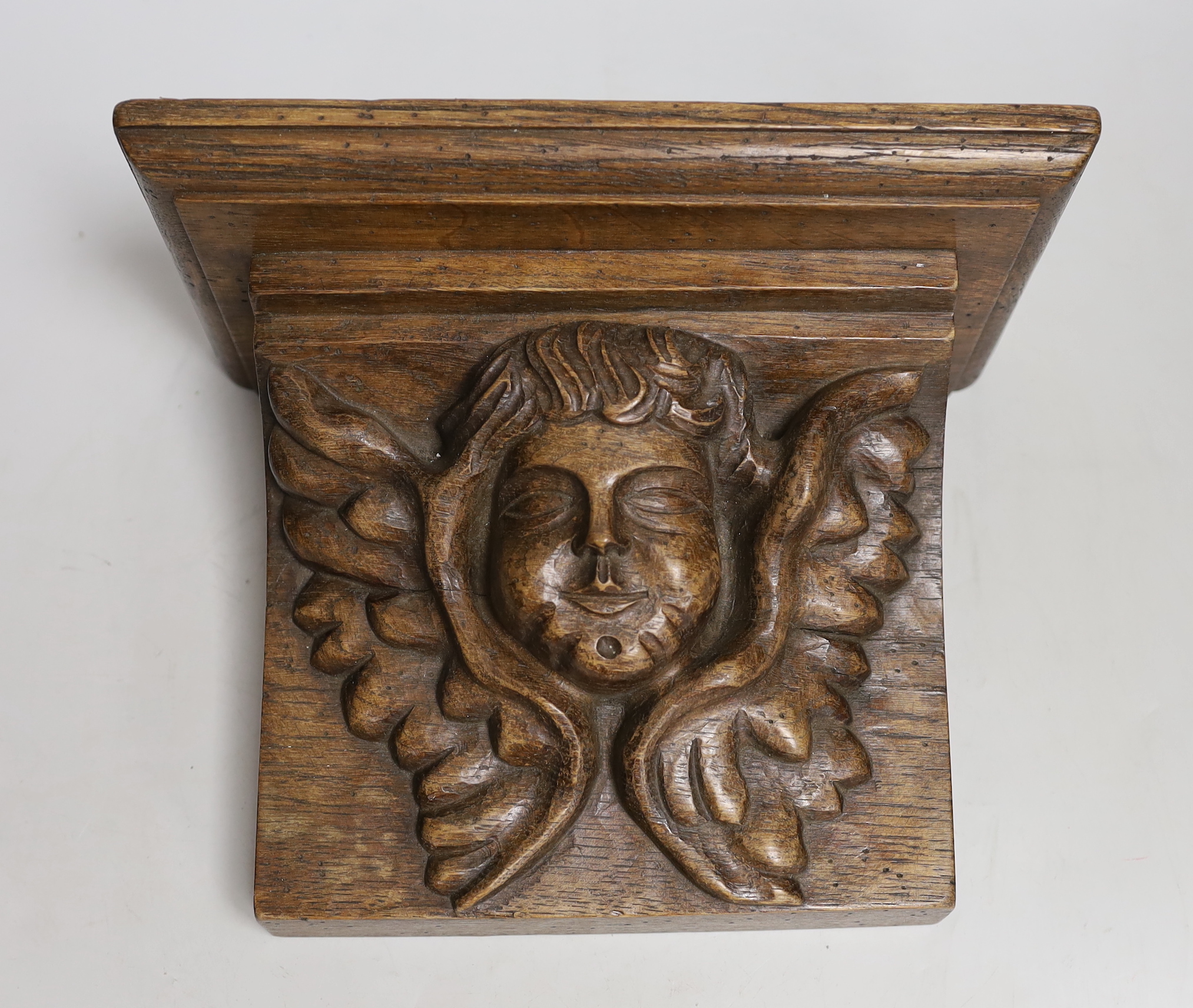 A carved oak 'angel' wall bracket, 26cm wide